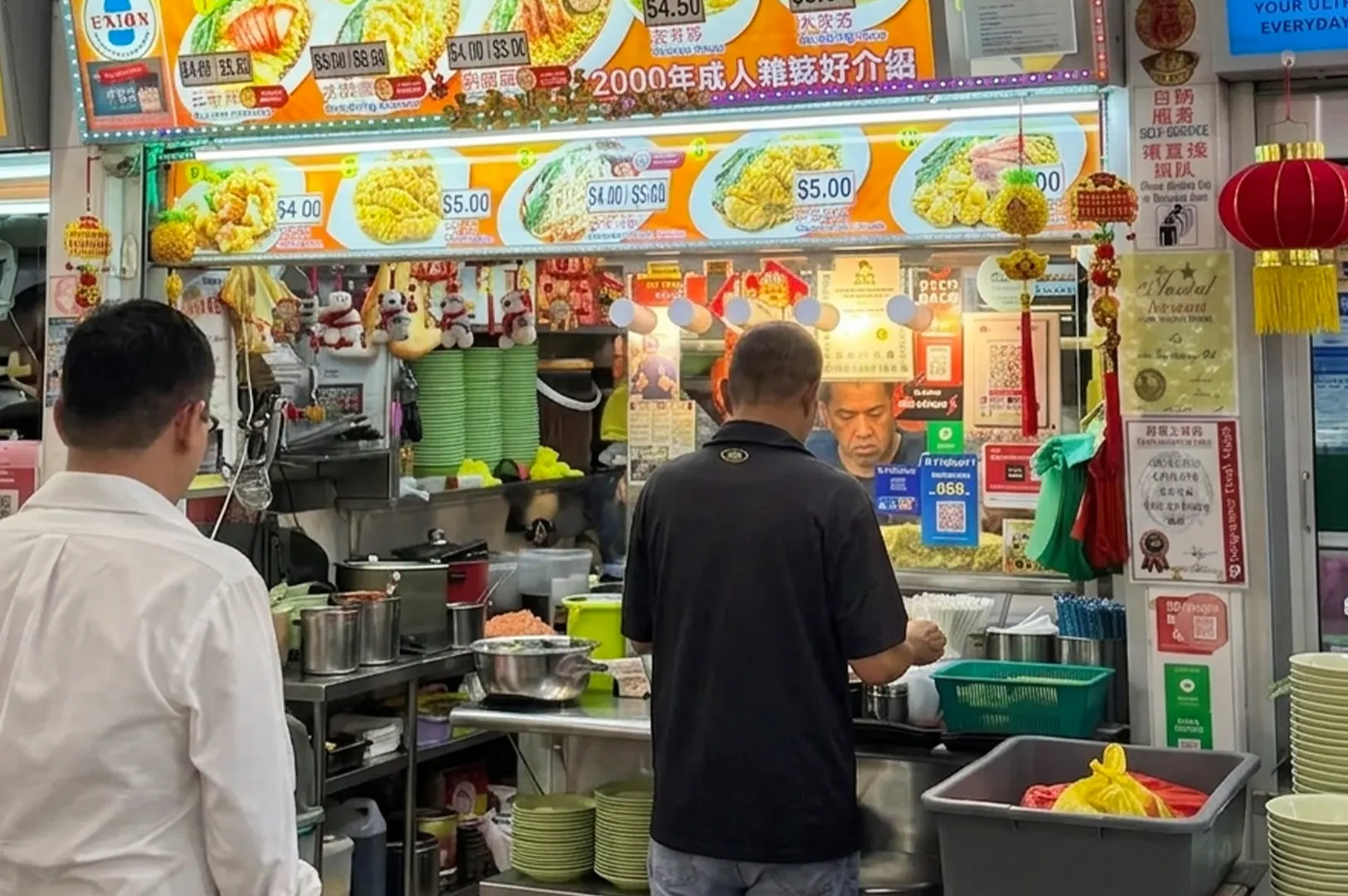 Customers waiting at a busy Singaporean hawker stall displaying colorful food menus.