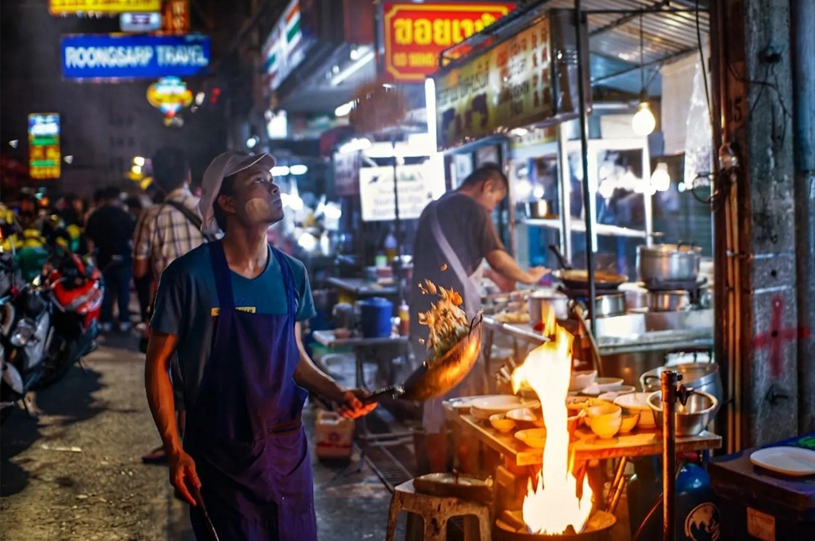 A street vendor tossing food high into the air from a wok over a large flame.