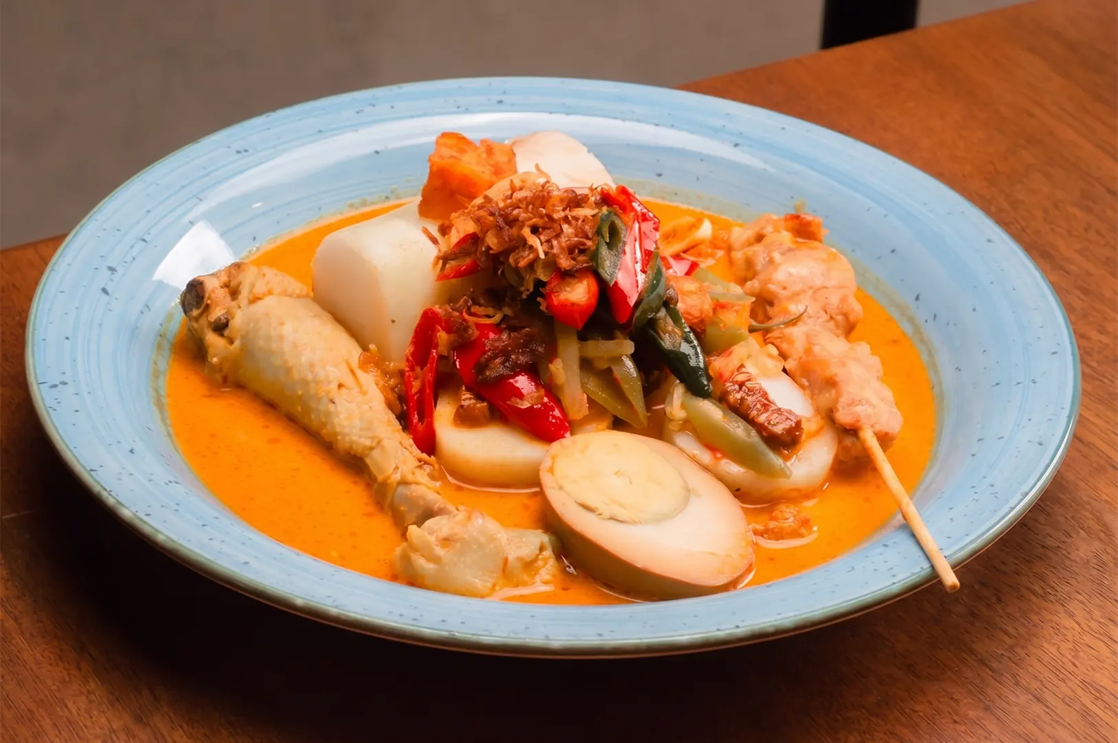 Indonesian Lontong Cap Go Meh with rice cakes, chicken drumstick, hard-boiled egg, and chicken satay in coconut milk curry