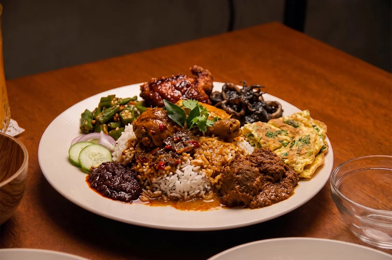 Malaysian Nasi Kandar plate with white rice drenched in mixed curries, fried chicken, beef rendang, omelet, okra, and sambal.